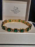Gold bracelet with green gemstones on a branded box