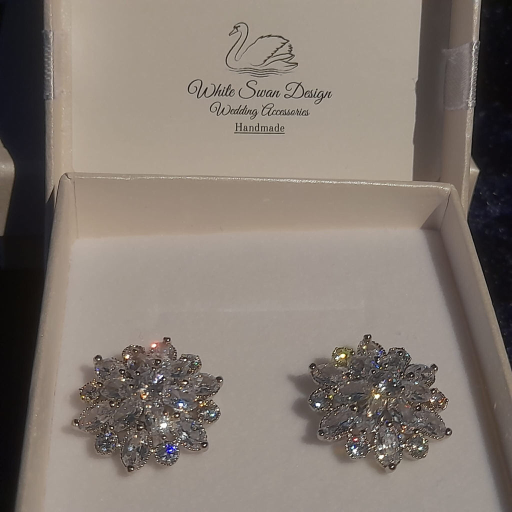 Silver floral earrings with clear stones on abox.