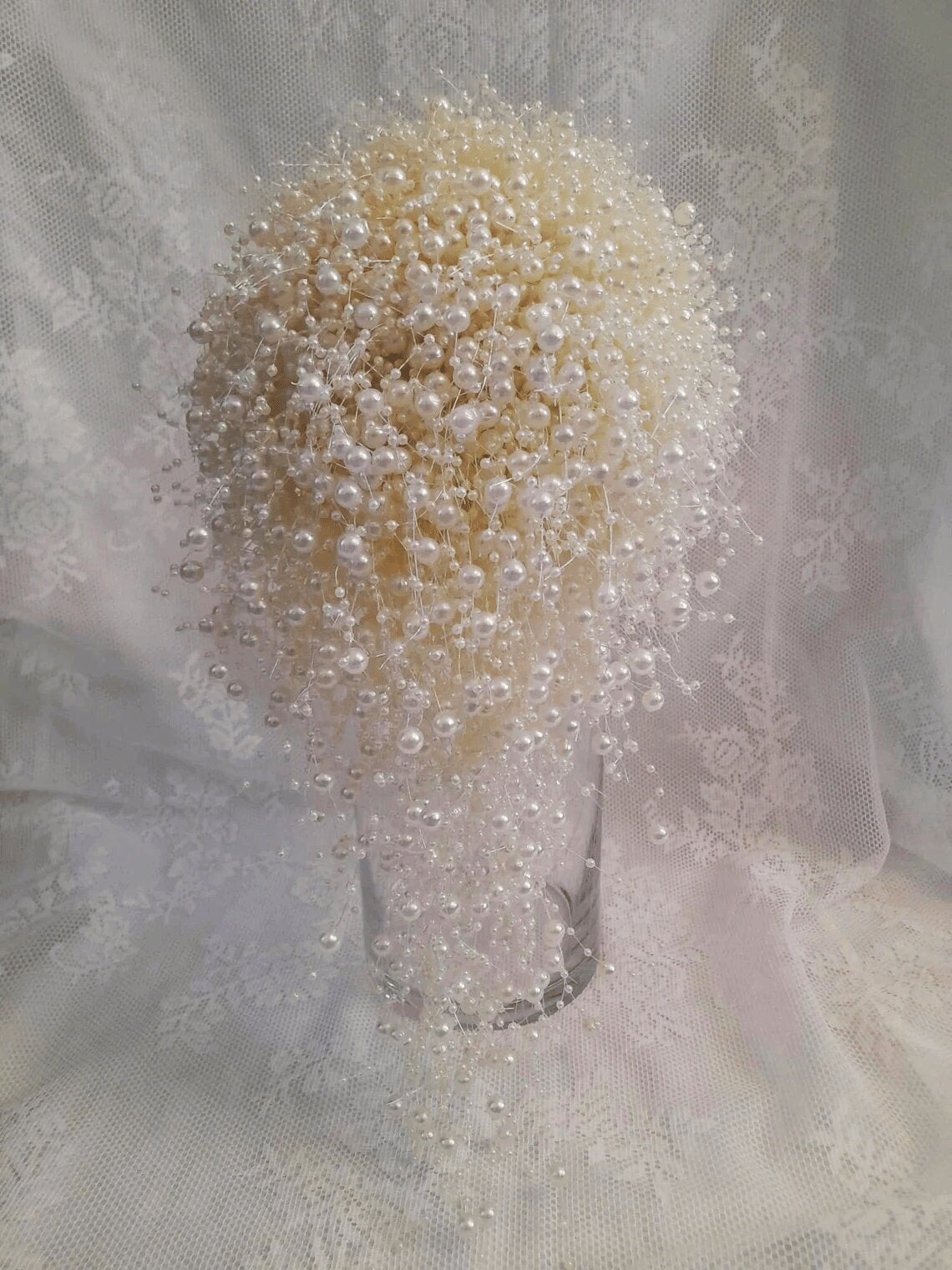 Ivory waterfall bouquet made of pearls on a textured fabric background