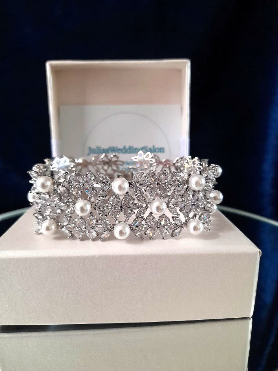 Silver bracelet with pearls on a white box with branding.