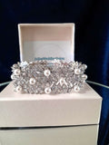 Silver bracelet with pearls on a white box with branding.