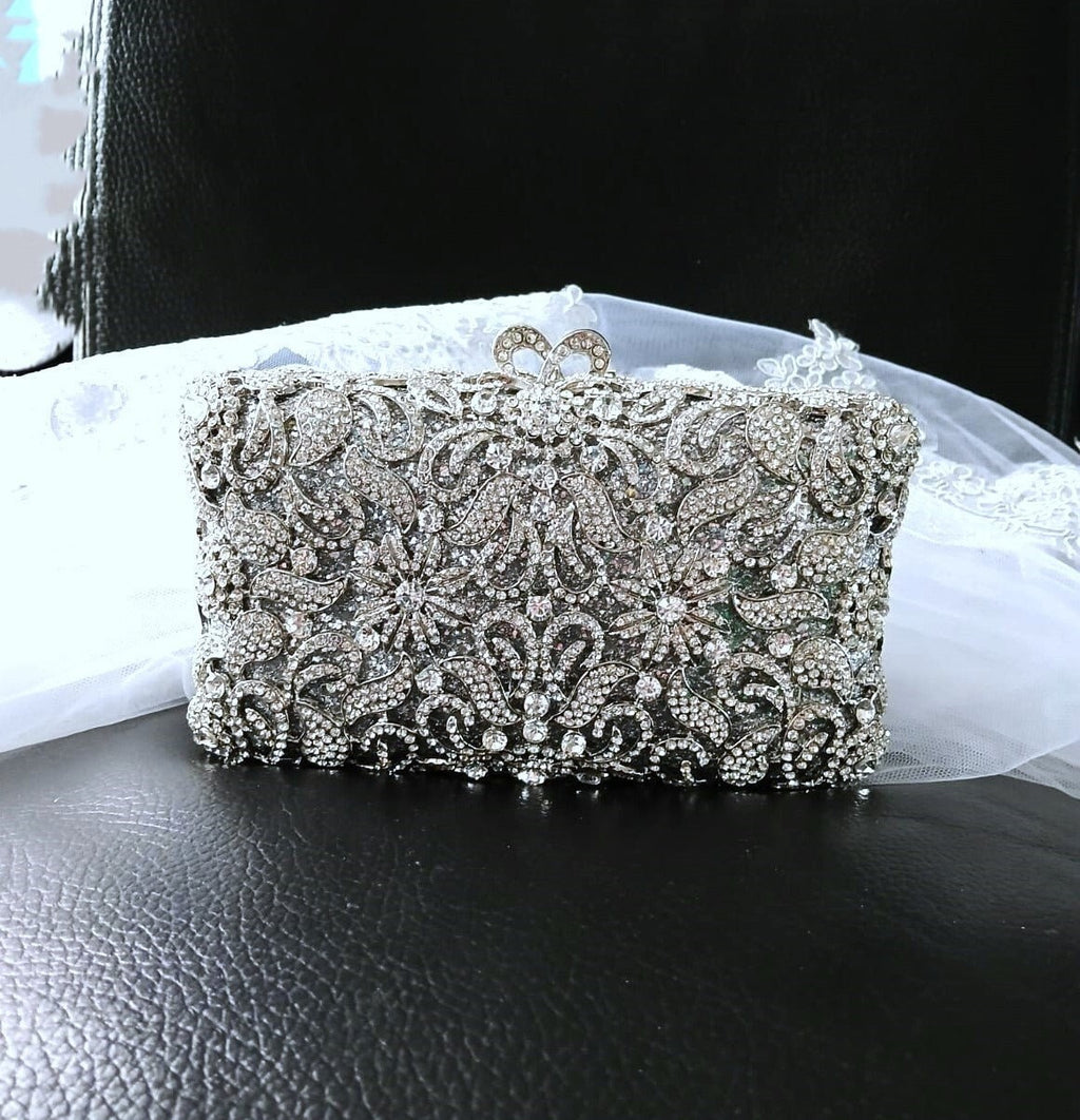 Silver crystal clutch bag in metal setting on a black surface with a white background