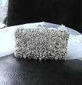 Silver crystal clutch bag in metal setting on a black surface with a white background