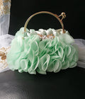 Mint green (sage green) floral handbag with gold accents on a dark surface