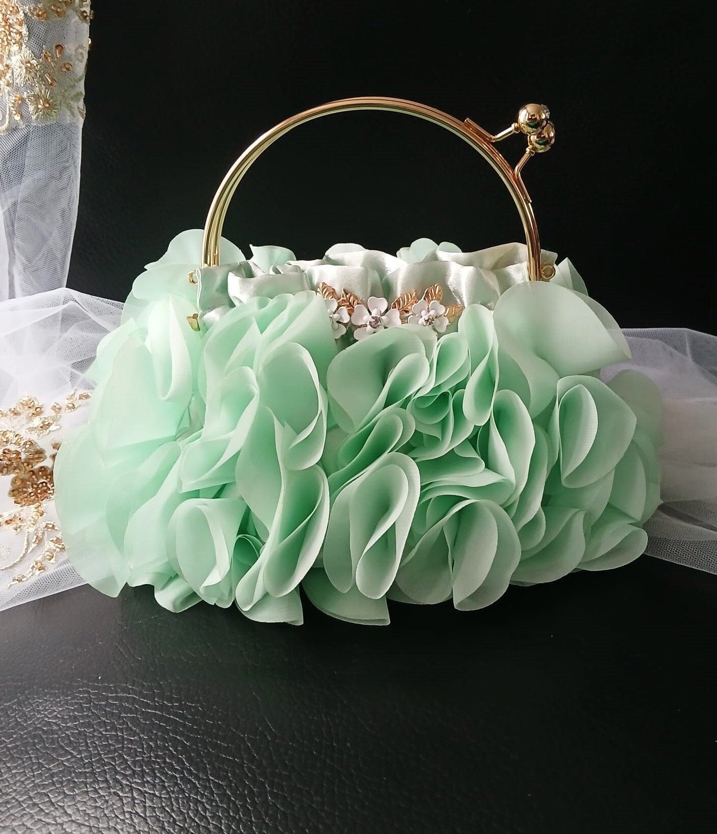 Mint green (sage green) floral handbag with gold accents on a dark surface