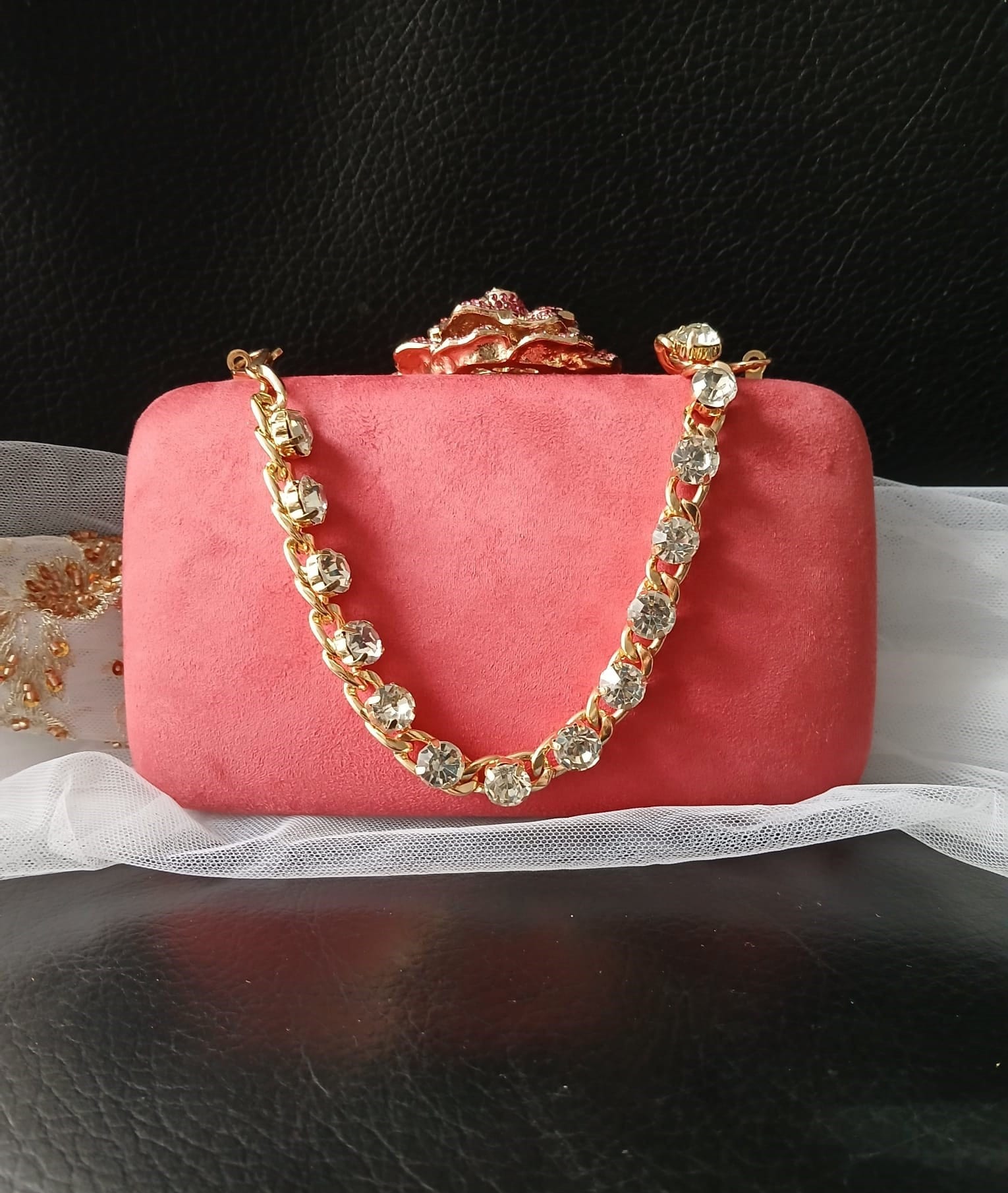 Coral red clutch bag with gold chain handle on a black background
