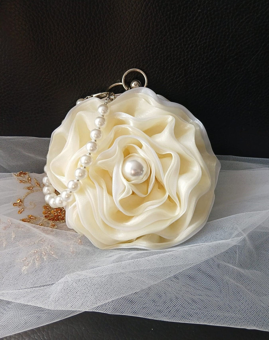 Ivory floral clutch with pearl handle on a black background