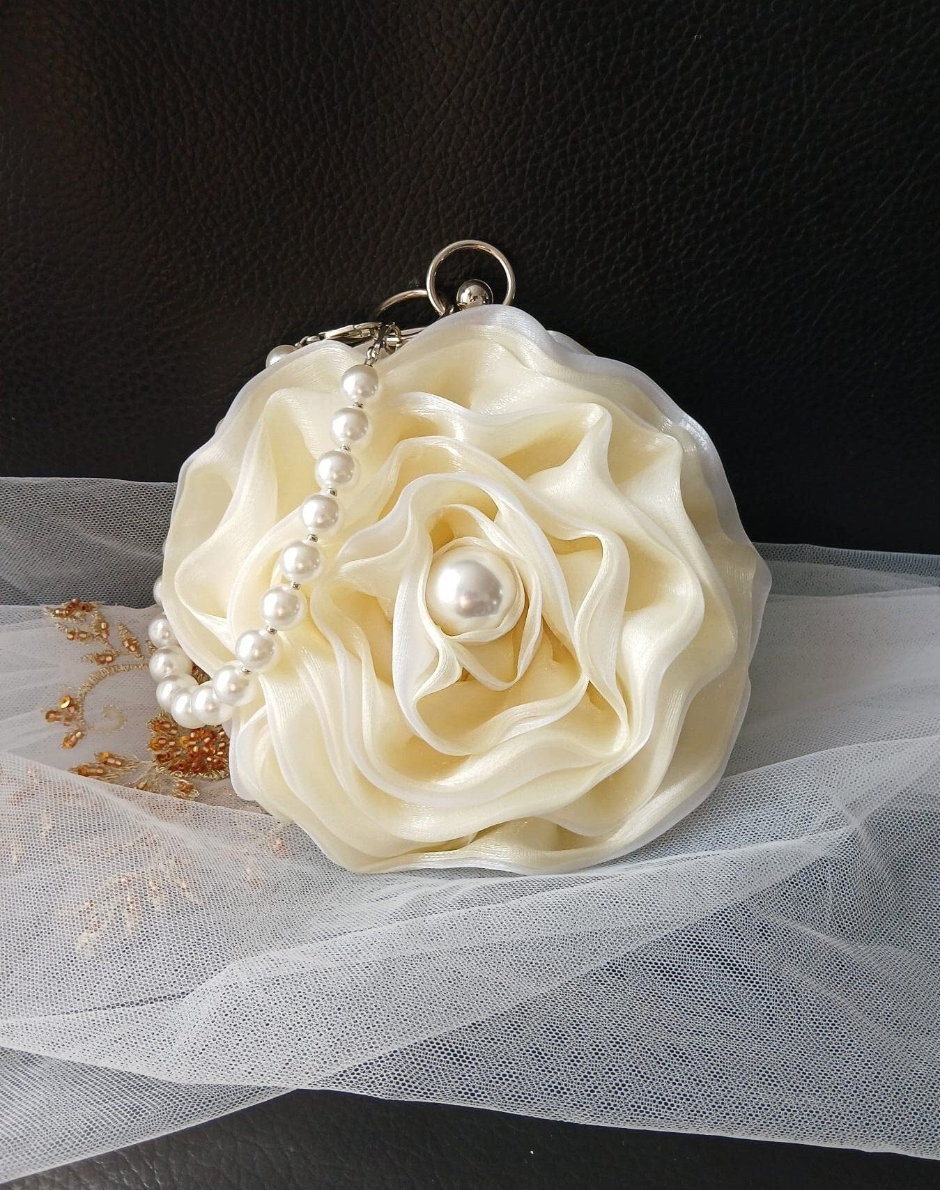 Ivory floral clutch with pearl handle on a black background