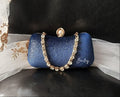 Blue glittery clutch with a gold crystal chain handle on a black surface.