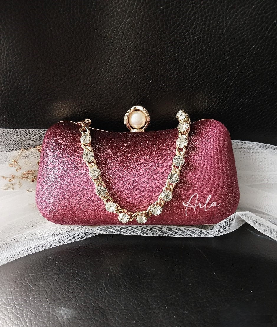 Wne Red clutch bag with decorative chain and pearl clasp on a black background
