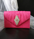 Fuchsia Pink clutch bag with a decorative brooch on a black background