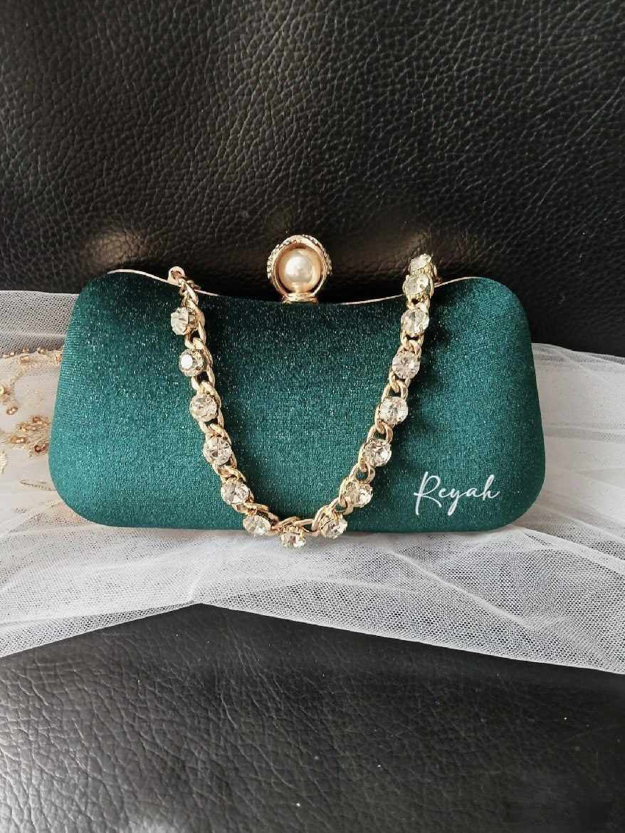 Green clutch with decorative chain and your text on a black background