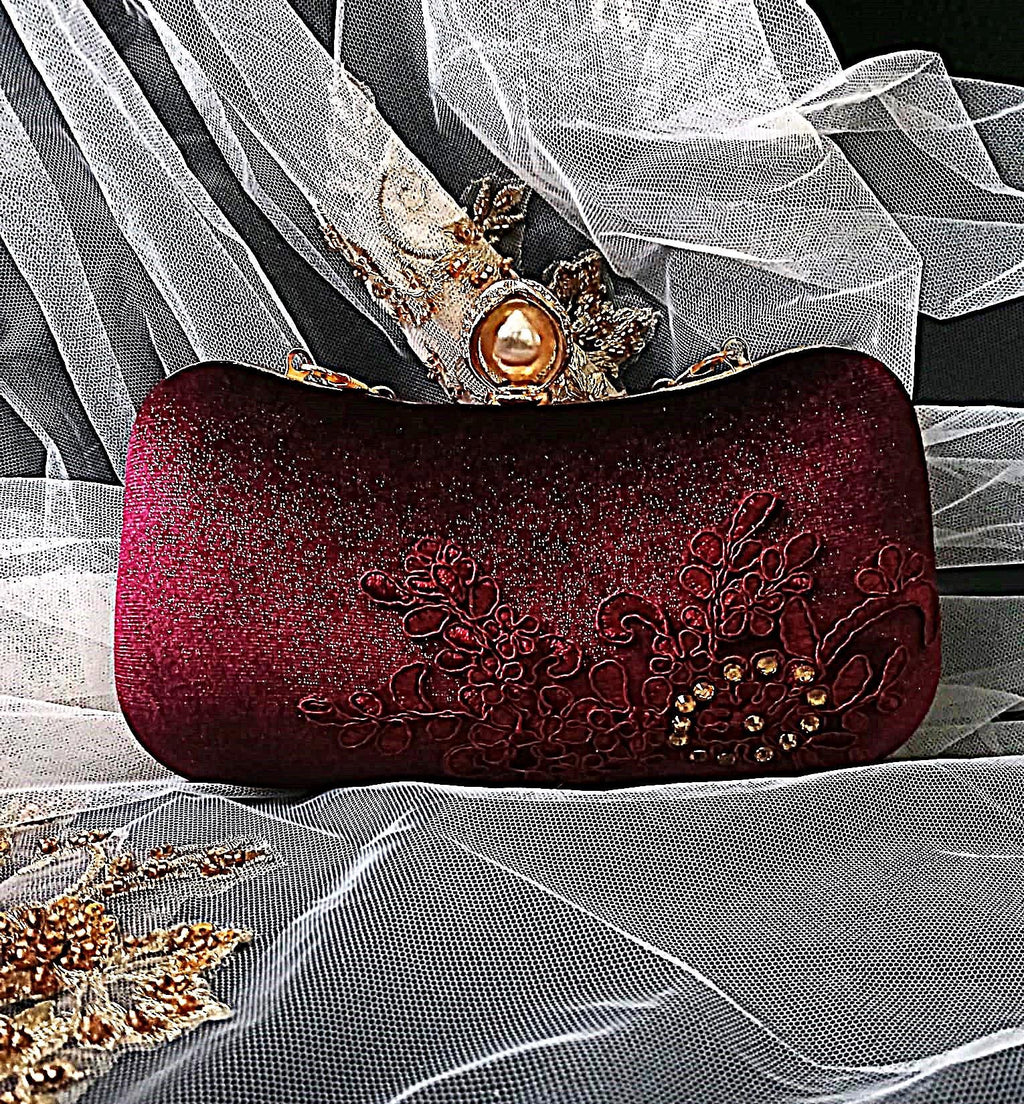 Wine Red clutch bag with floral embroidery on a white fabric background