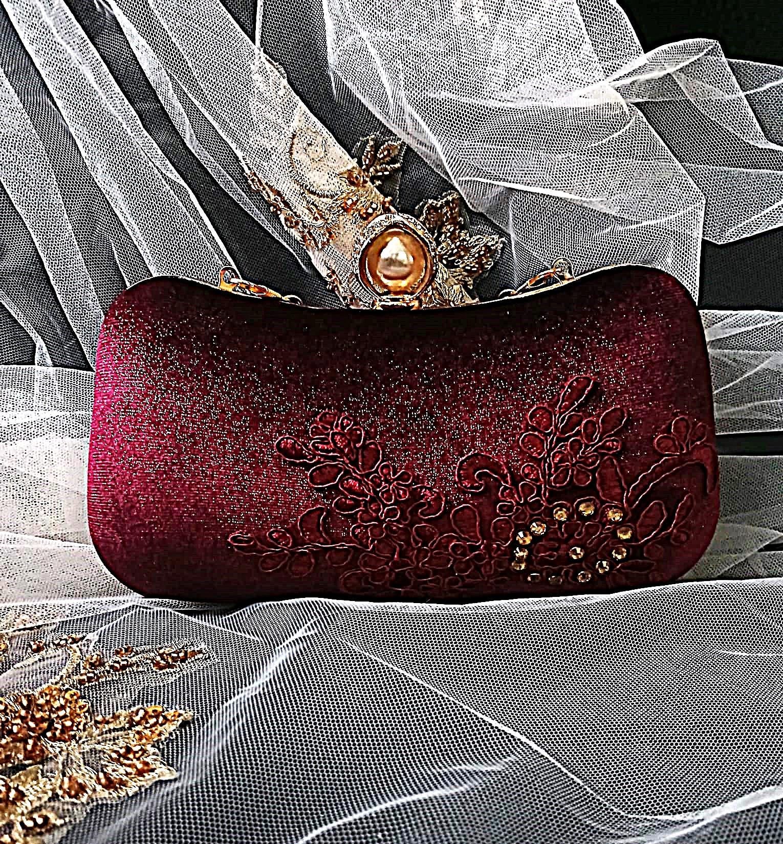 Wine Red clutch bag with floral embroidery on a white fabric background