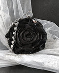 Black rose-shaped handbag with silver crystal chain on a white lace background