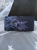 Navy blue clutch with floral lace detailing on a textured surface