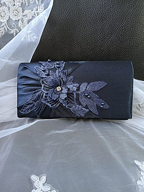 Navy blue clutch with floral lace detailing on a textured surface