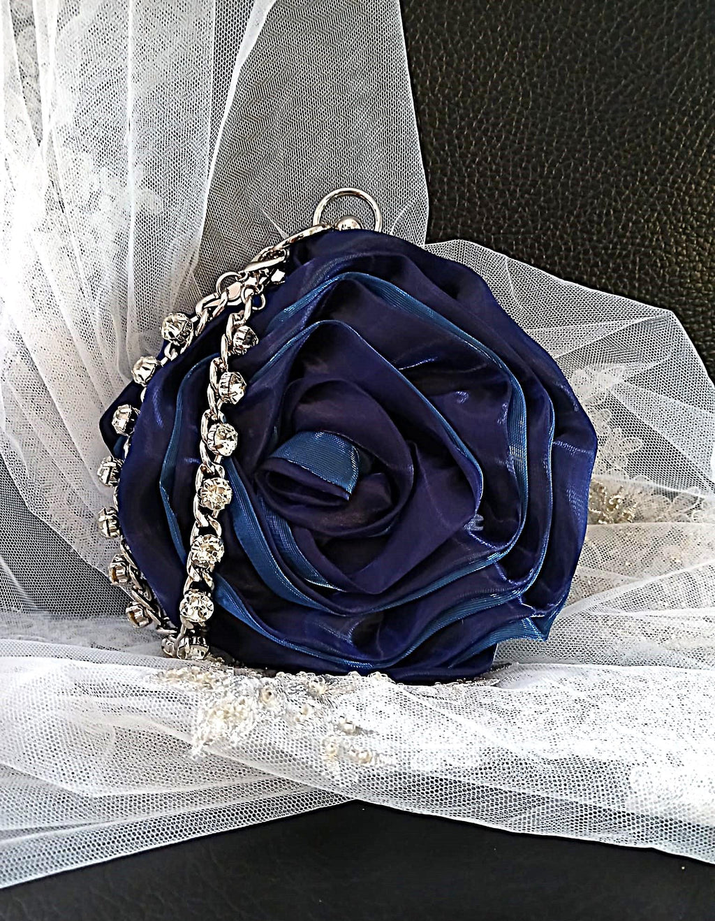 Navy blue rose-shaped handbag with decorative crystal silver chain on a white tulle background