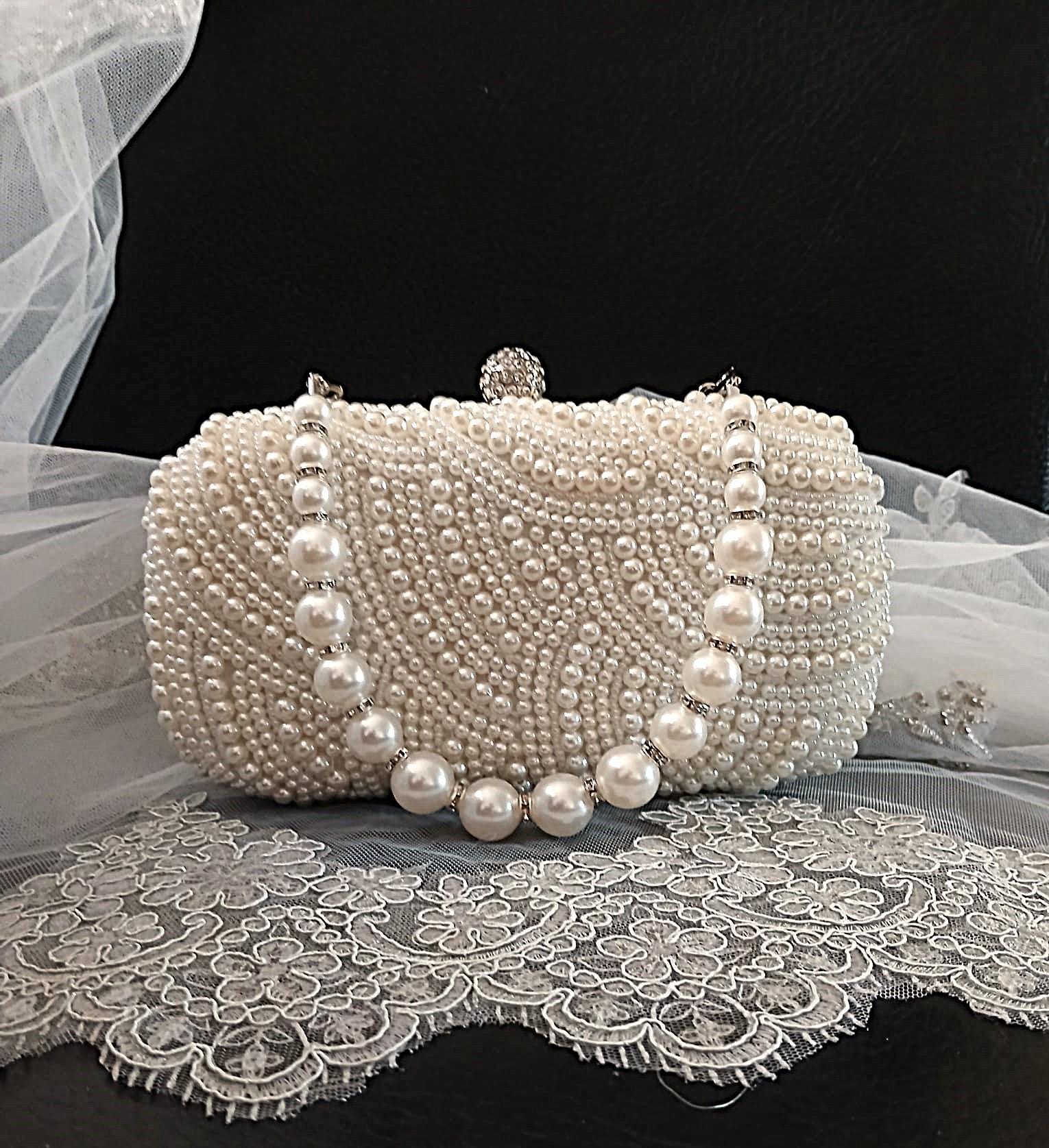 Pearl clutch bag in silver frame on a lace surface with a black background