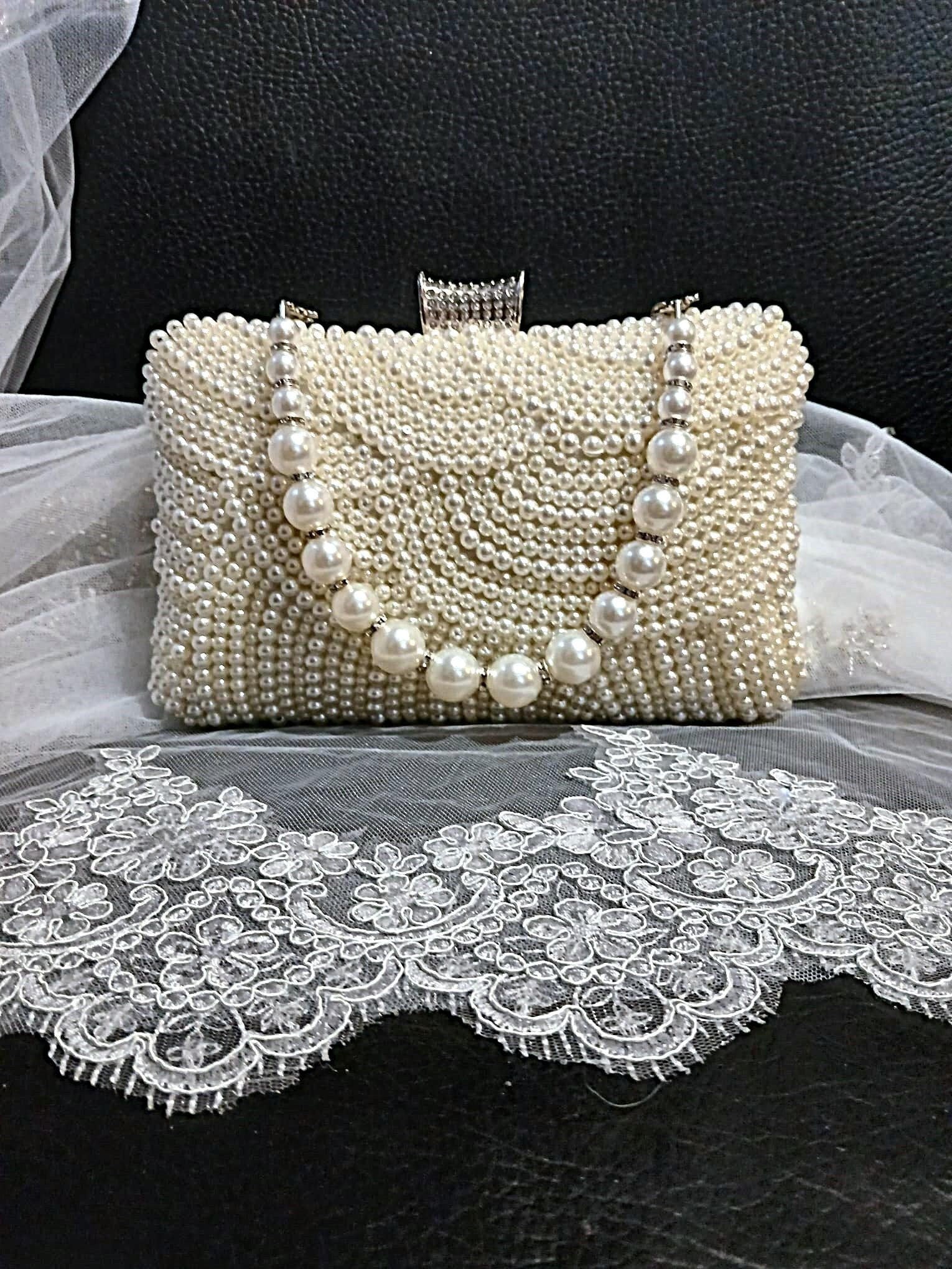 Pearl clutch bag in silver frame on a black background with lace fabric
