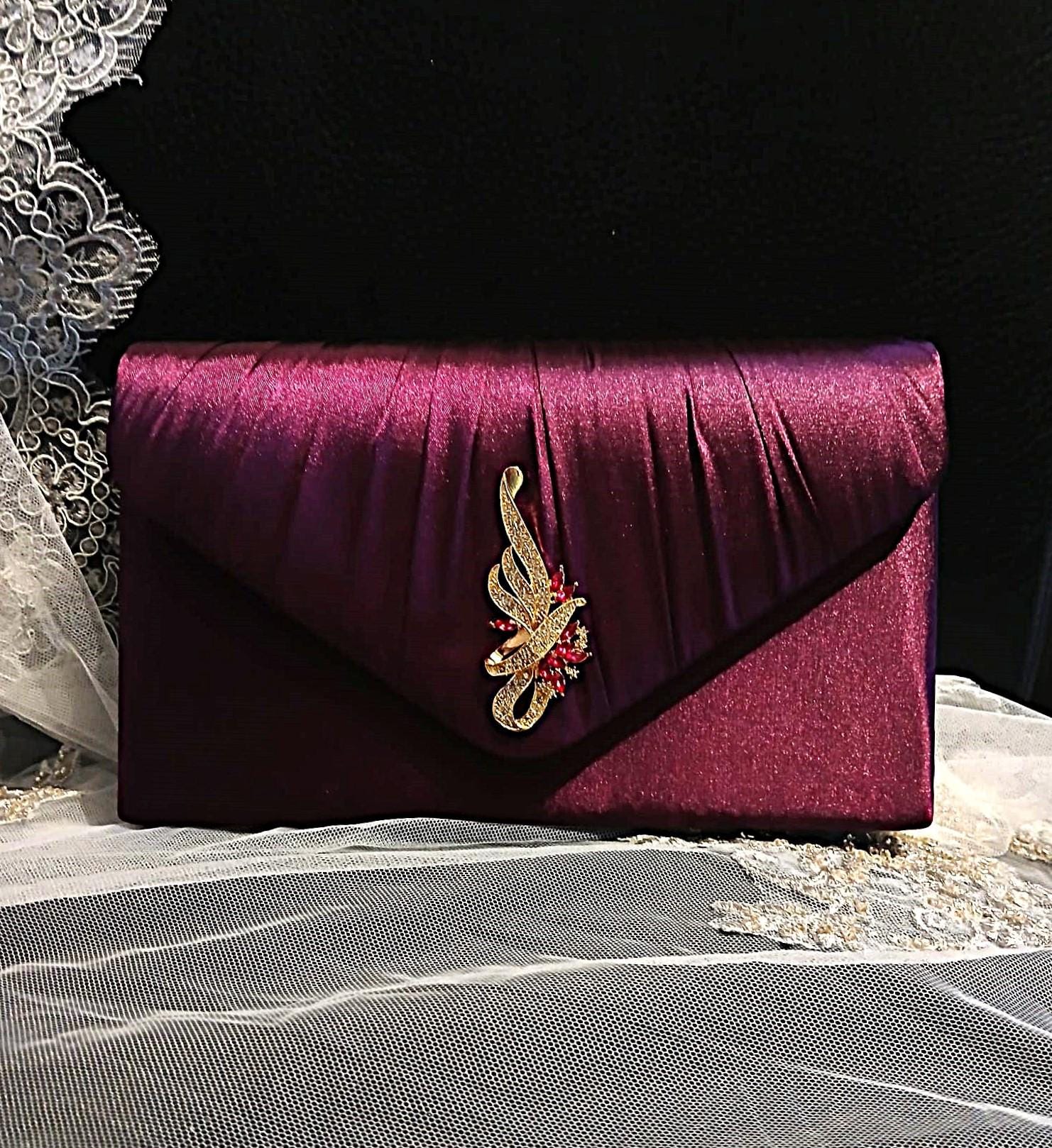 Dark Purple clutch bag with a decorative brooch on a textured surface