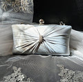 Silver clutch bag with decorative bow on a black background