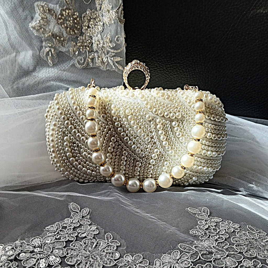 Pearl clutch bag in with gold harware on a decorative fabric background