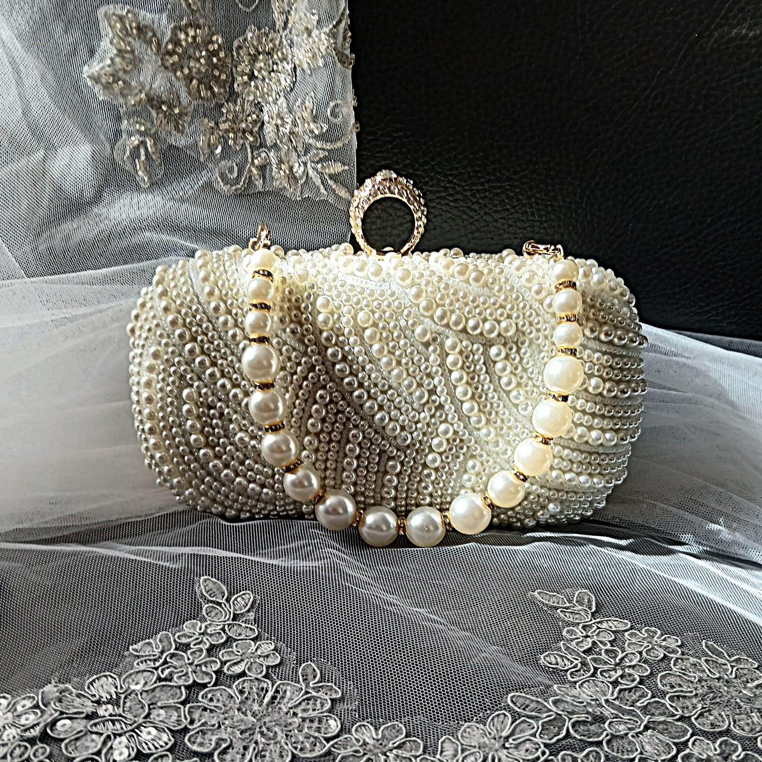 Pearl clutch bag in with gold harware on a decorative fabric background