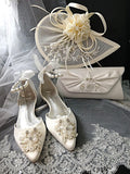 White wedding shoes with floral embellishments, matching hat, and clutch on a lace fabric background.