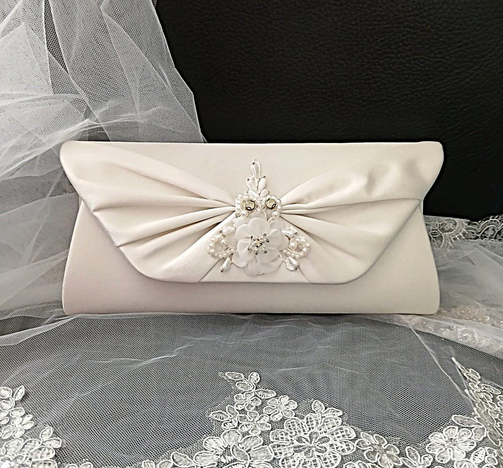 Ivory clutch bag with floral embellishments on a lace fabric background