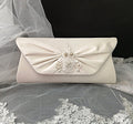 Ivory clutch bag with floral embellishments on a lace fabric background