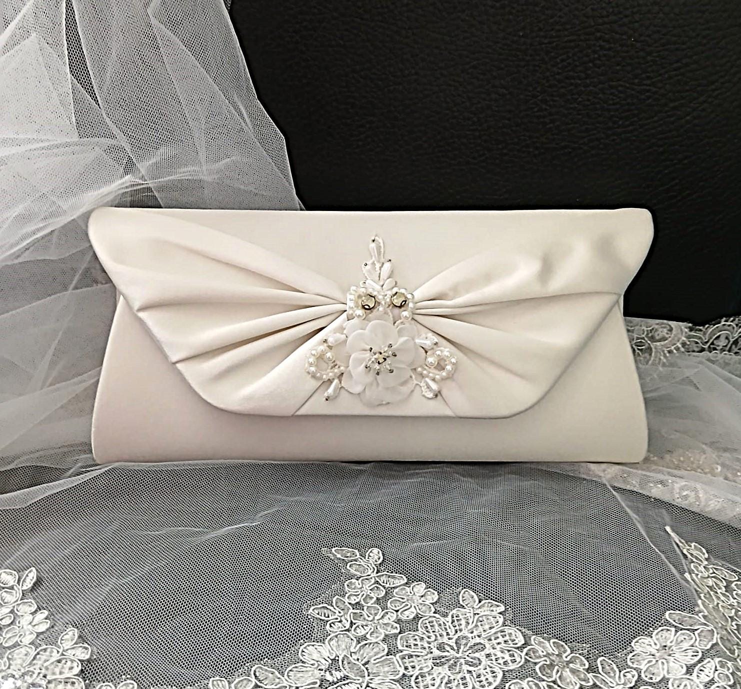 Ivory clutch bag with floral embellishments on a lace fabric background