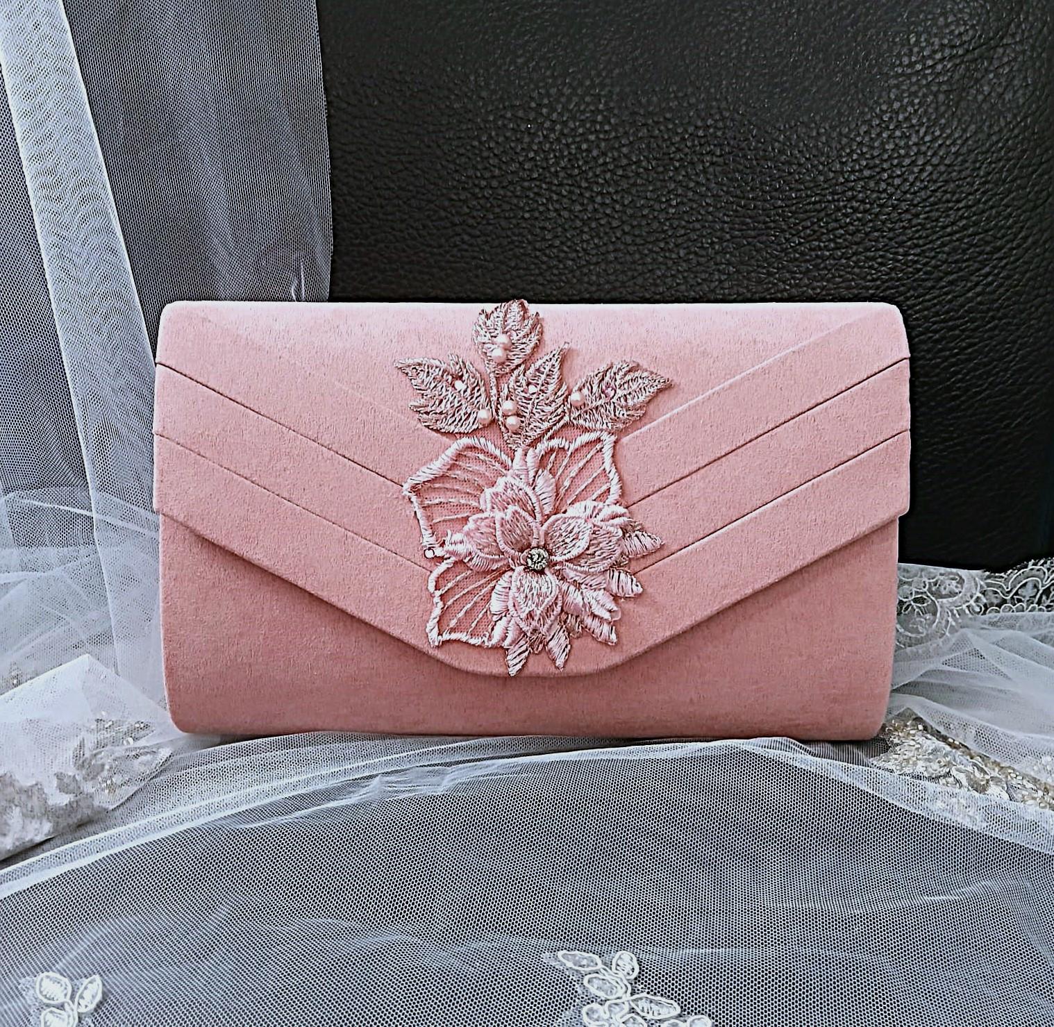 Pink clutch bag with floral embroidery on a black background