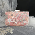 Pink clutch bag with floral and lace details on a tulle background