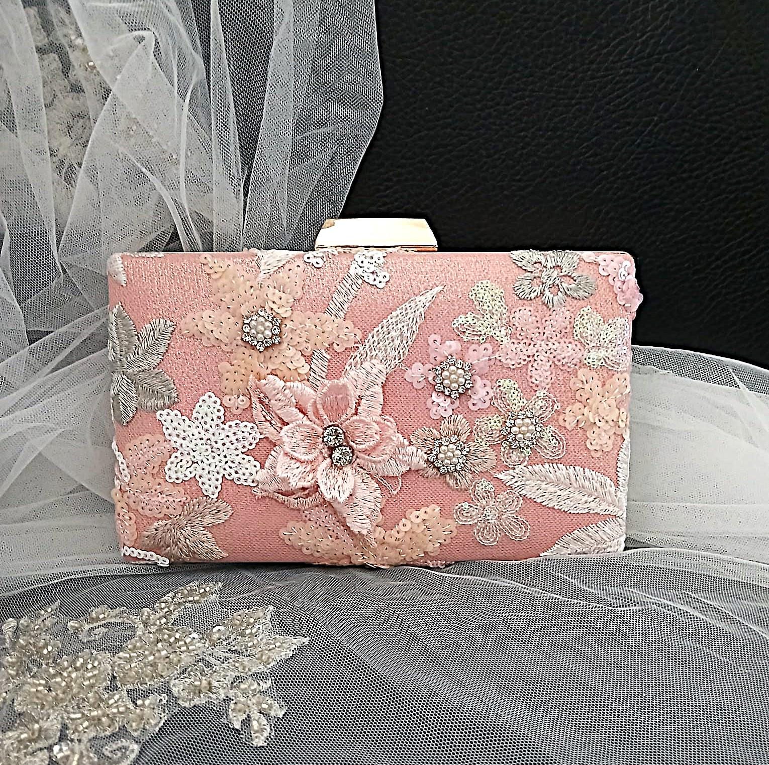 Pink clutch bag with floral and lace details on a tulle background