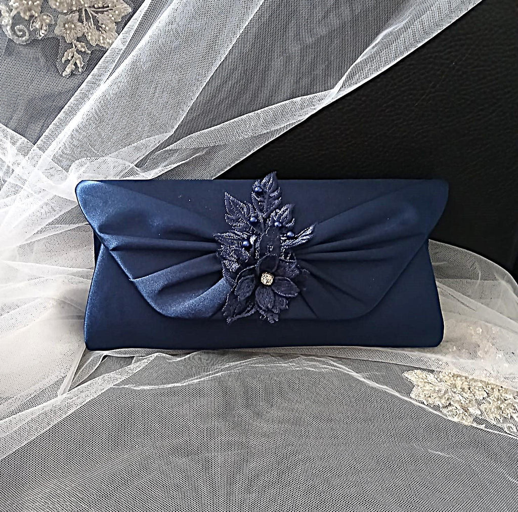 Navy blue clutch with floral embellishment on a veil background