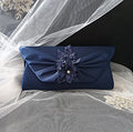 Navy blue clutch with floral embellishment on a veil background
