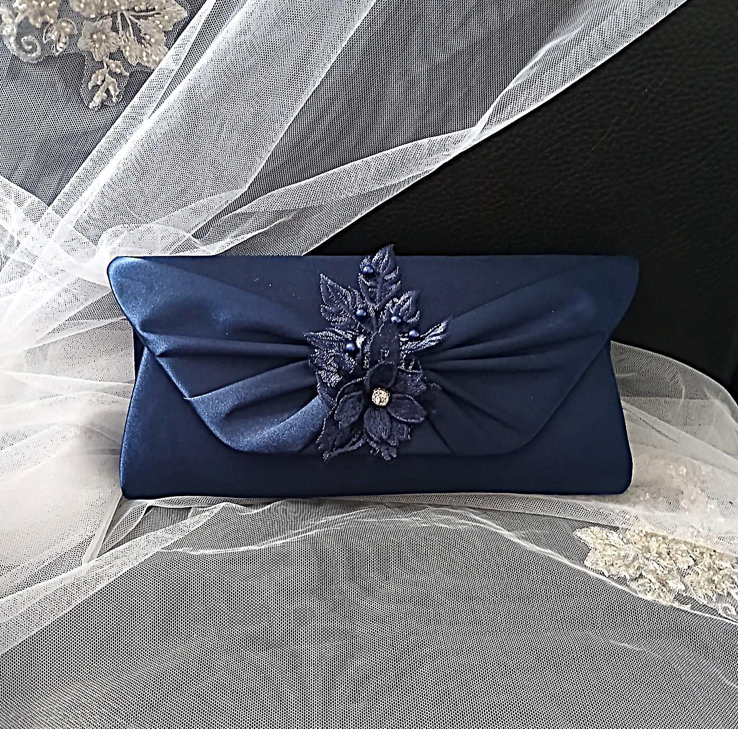 Navy blue clutch with floral embellishment on a veil background
