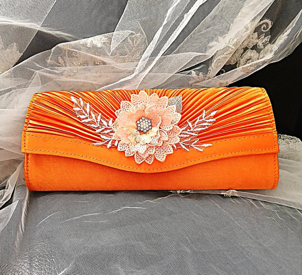 Orange clutch with floral embellishments on an orange fabric background