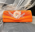 Orange clutch with floral embellishments on an orange fabric background