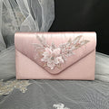 Pink clutch bag with floral embroidery on a decorative background