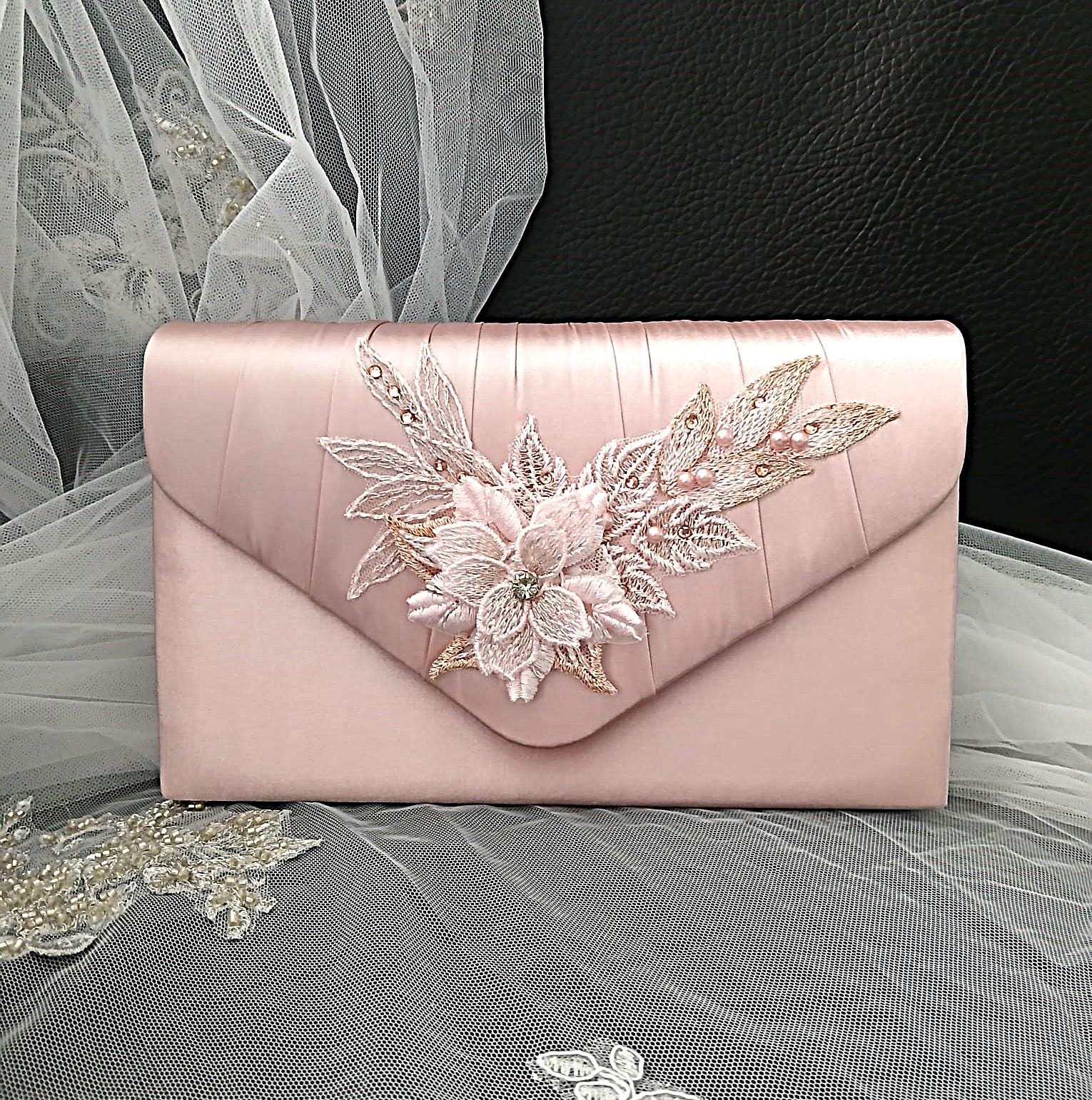 Pink clutch bag with floral embroidery on a decorative background