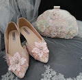 Pair of pink shoes with floral embellishments and a matching clutch bag on a gray fabric background.