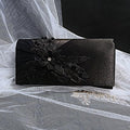 Black clutch bag with floral design on a white lace background