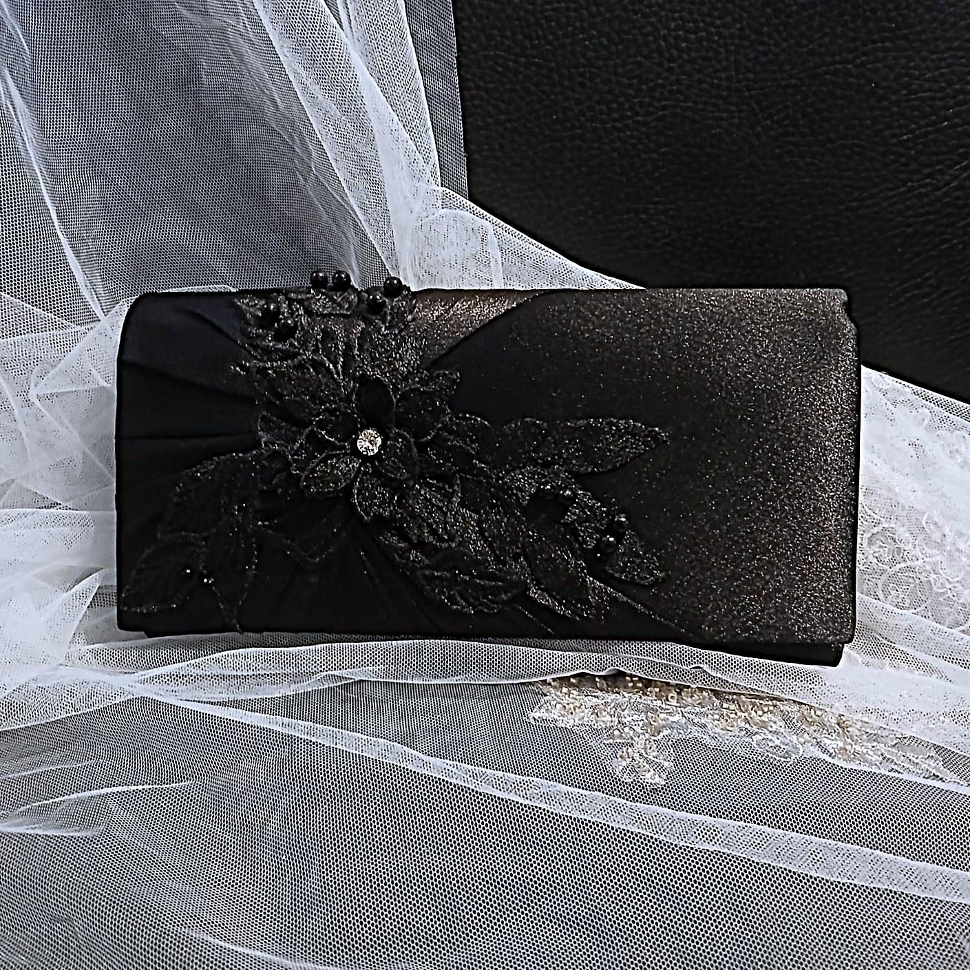 Black clutch bag with floral design on a white lace background