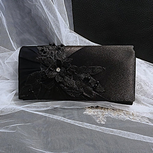 Black clutch bag with floral design on a white lace background
