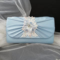 Light blue clutch bag with floral embellishment on a satin background