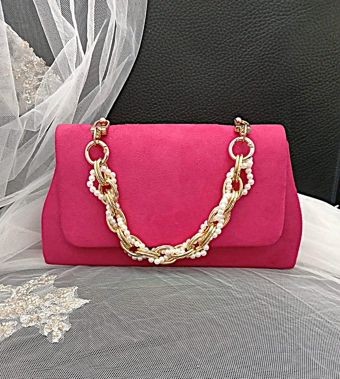 Fuchsia Pink handbag with gold chain handle on a black background