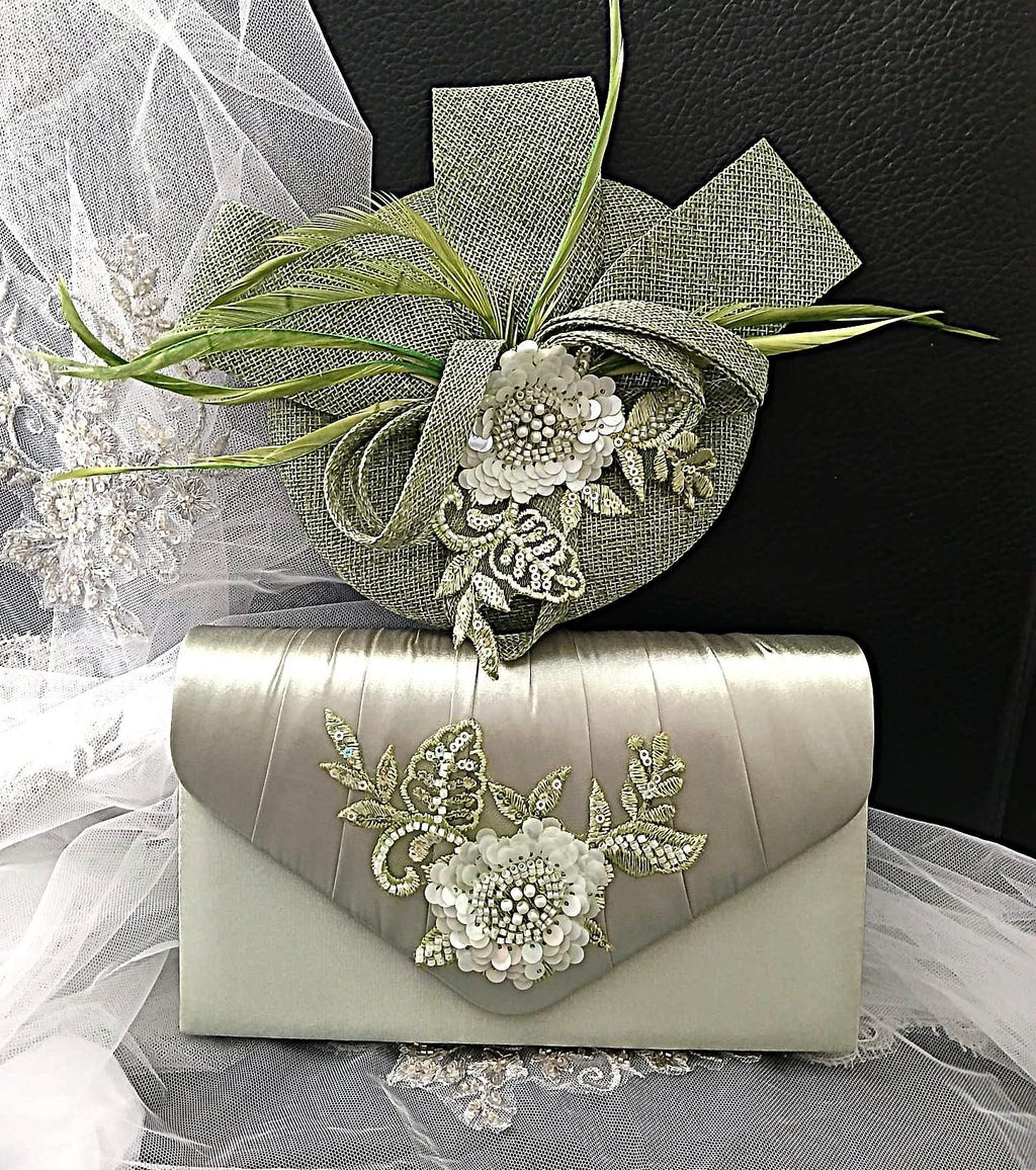 Sage green clutch bag and hat with floral embellishments on a black background