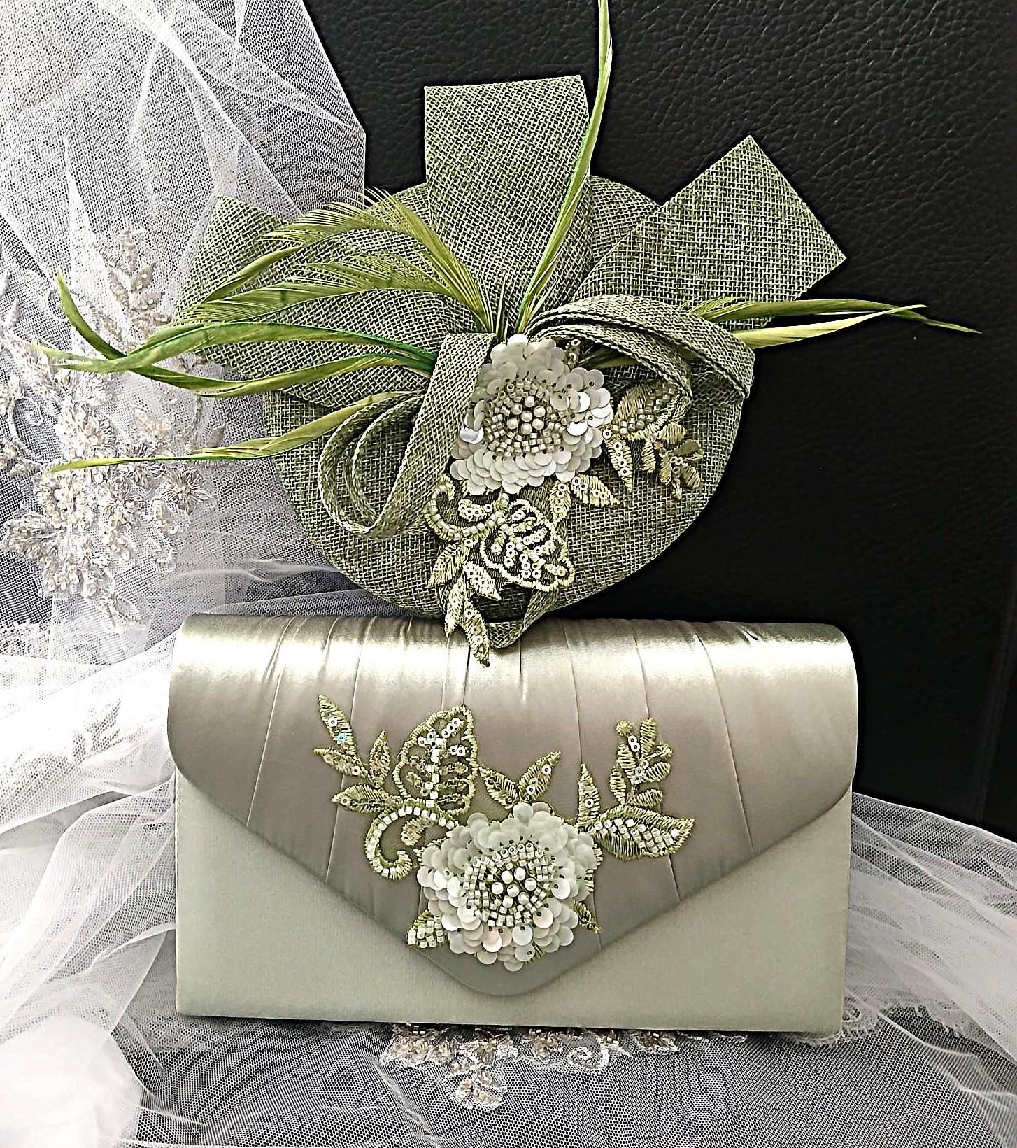 Sage green clutch bag and hat with floral embellishments on a black background
